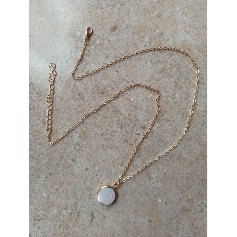Collar de cadena fina dorada con un colgante circular plano fabricado en concha de perla natural que refleja destellos irisados.