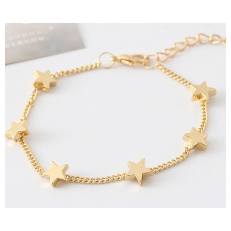 Pulsera de cadena fina bañada en oro con varios dijes colgantes en forma de estrella pulida.