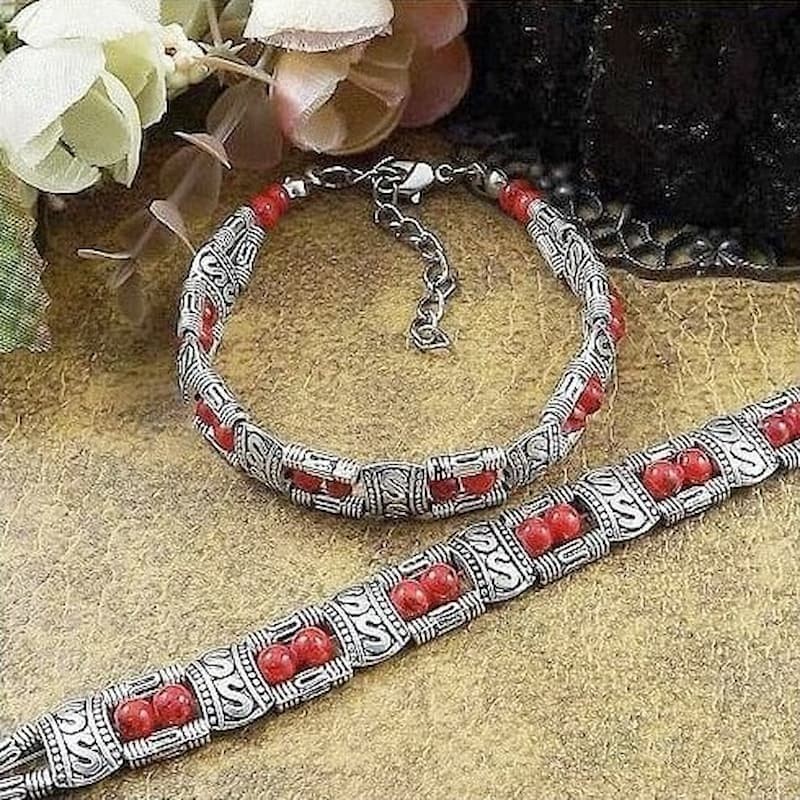 Pulsera de metal con relieves grabados y piezas centrales de piedras rectangulares en color rojo vibrante y negro azabache.