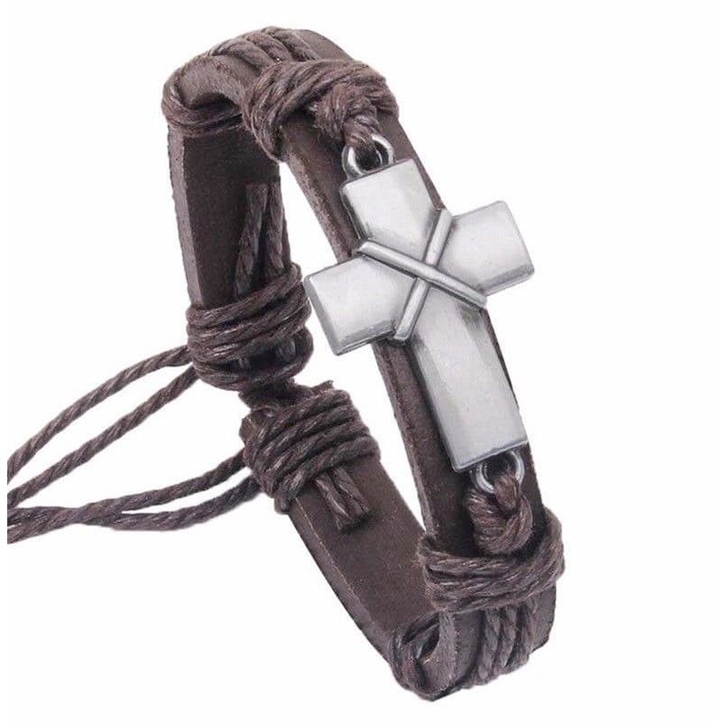Brazalete de cuero marrón con placa central de metal grabada con una cruz de estilo minimalista.
