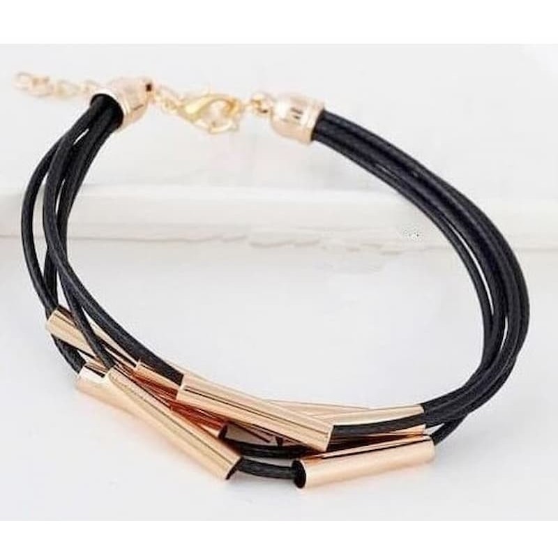 Pulsera para mujer compuesta por múltiples cordones de piel fina y piezas tubulares de metal dorado brillante.