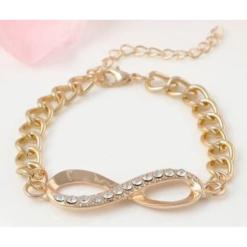 Pulsera de cadena de acero dorado con piezas circulares incrustadas de piedras blancas de acabado brillante.
