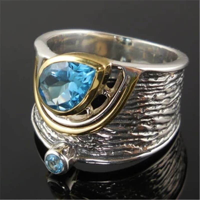 Anillo de estilo étnico con piedras azules en forma de gota de agua engastadas en metal labrado.