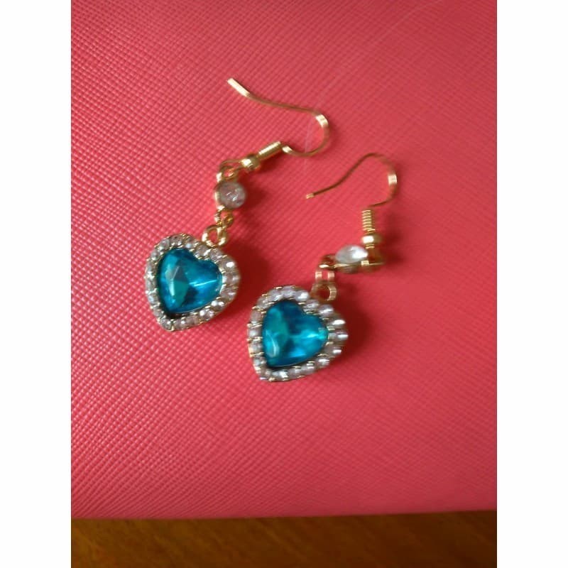 Pendientes colgantes con forma de corazón azul océano rodeado de cristales blancos brillantes sobre base chapada en plata.