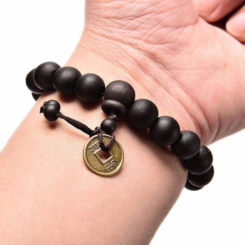 Pulsera de cuentas de madera natural con diseño de rosario budista y detalle de borla o nudo místico.