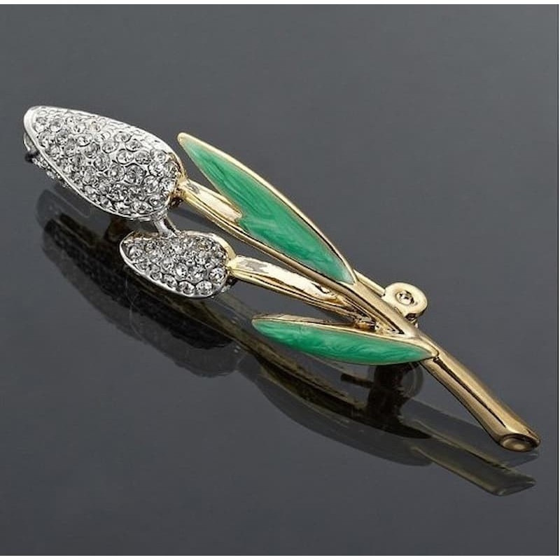 Broche de estilo vintage para vestidos de fiesta con diseño de hojas esmaltadas en color verde y cristales blancos brillantes.