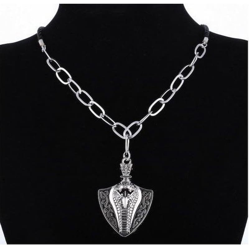 Colgante de acero inoxidable con forma de cobra en posición de ataque y relieve detallado sobre cadena larga de eslabones.