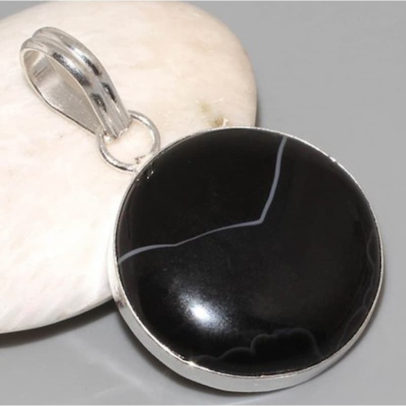 Colgante circular de acero chapado en plata con una piedra central de color negro tipo ónix.