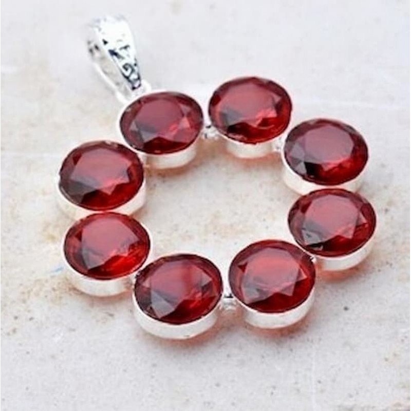 Colgante circular de acero con incrustaciones de piedras garnet de color rojo granate intenso.